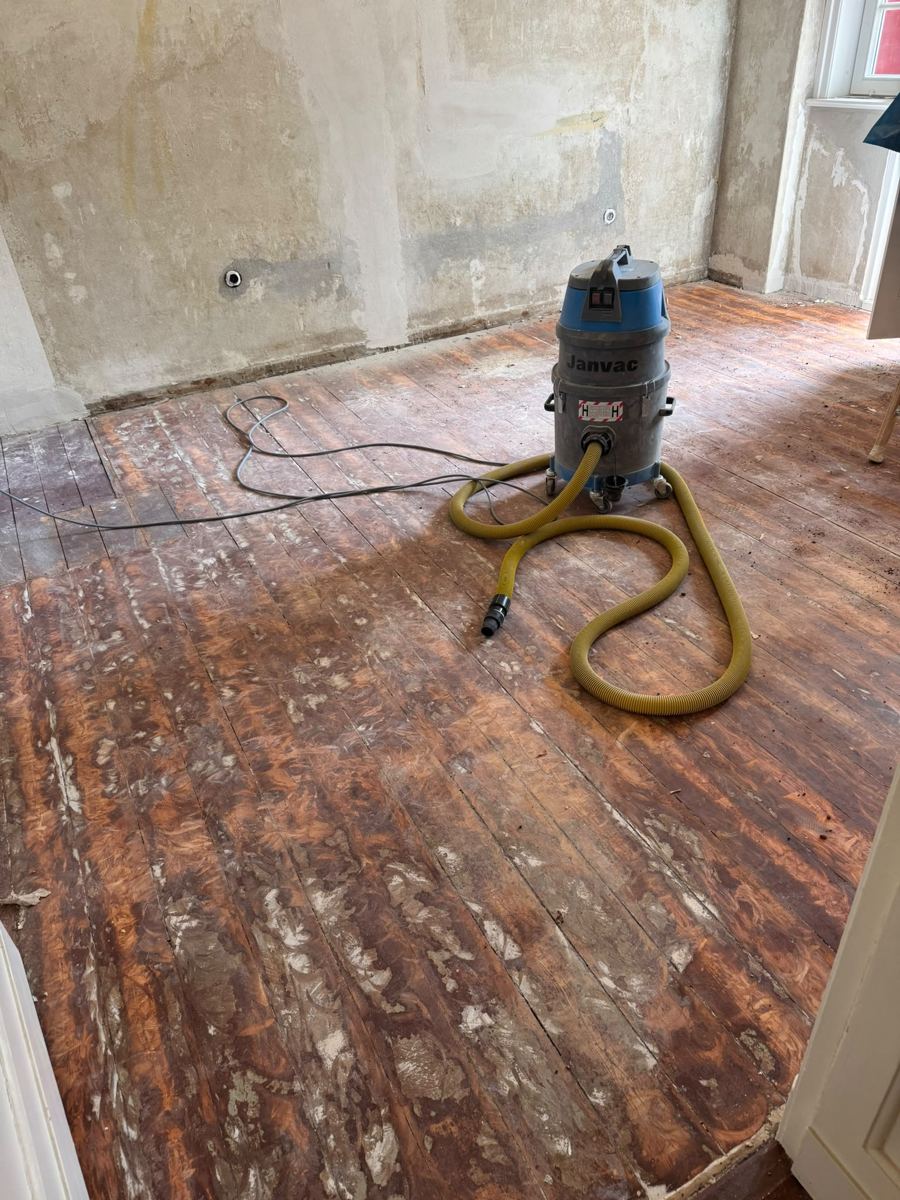 Old pine floorboards covered in paint and filler residues at takeover