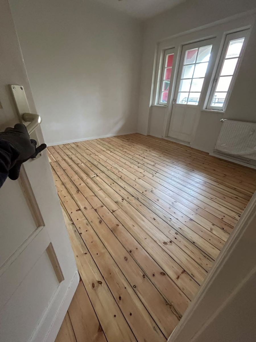 Finished sanded and sealed pine floorboards, room with balcony door