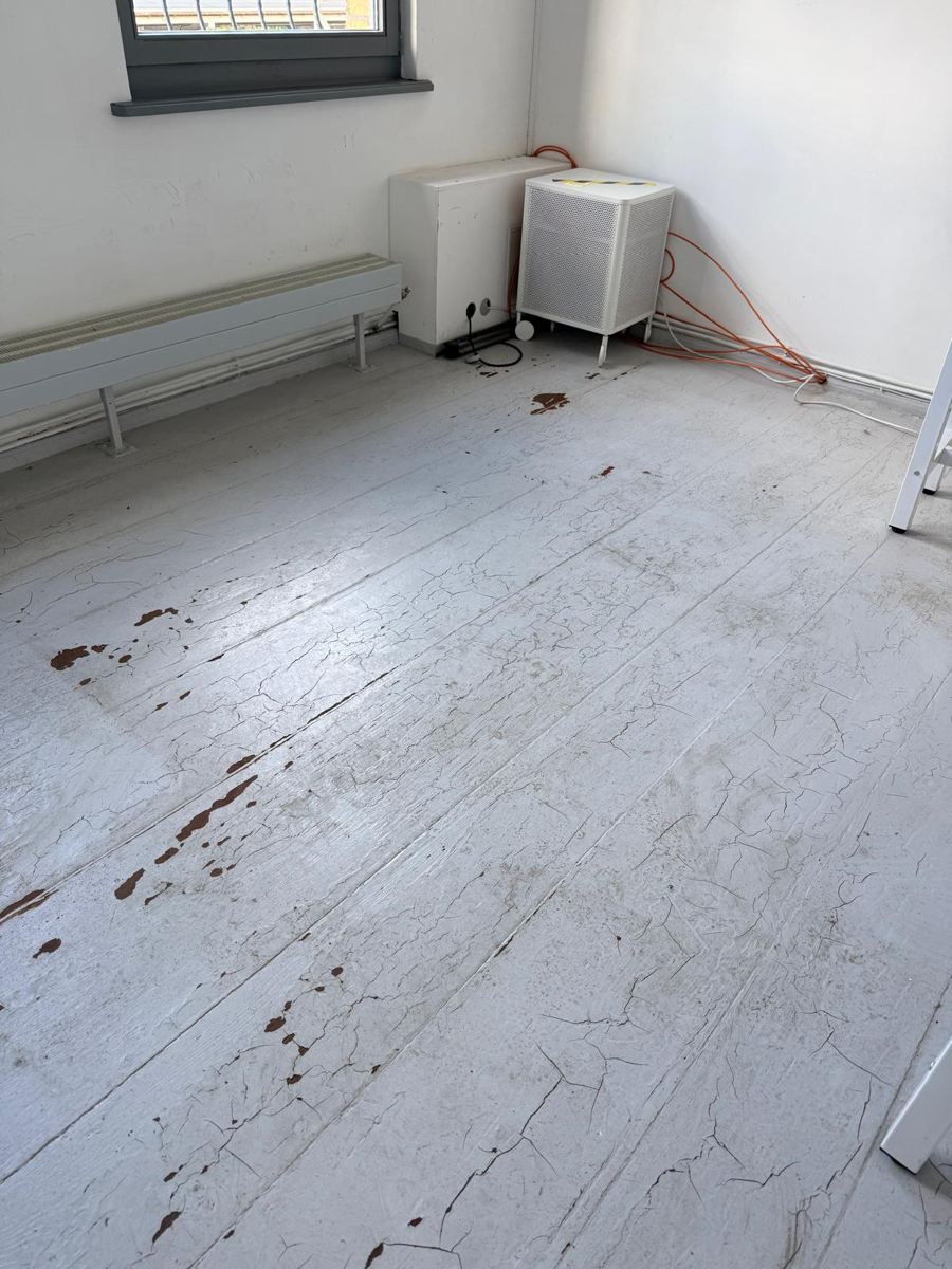 Floorboards with cracked, flaking old paint before restoration