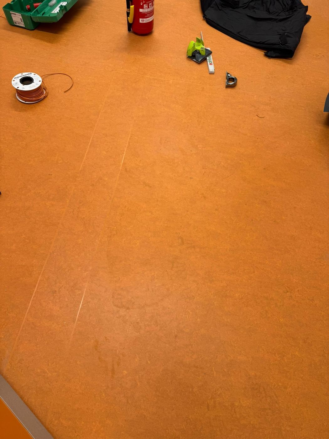 Orange linoleum with Marmoweld welding rod and tools during thermal seam welding