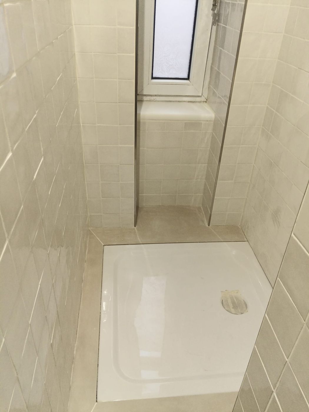 Tiled bathroom with shower tray and window