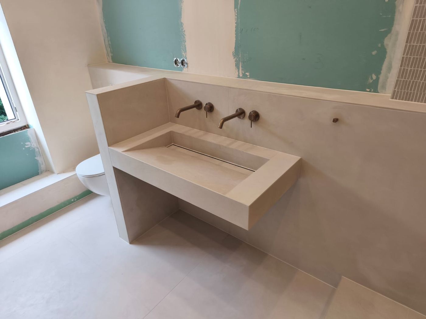 Seamless concrete-look washbasin with wall-mounted taps