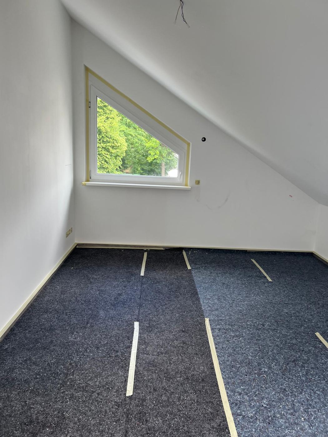 Sloped attic ceiling with triangular window cleanly painted